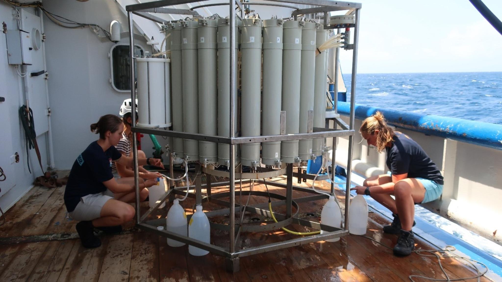 Two persons are on-board sampling of seawater using Niskin bottles that captured seawater over a range of water depths.