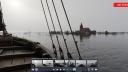A still from a virtual reality tour. In the front there is part of a ship, as if you are standing on deck, and looking out over the water. At the horizon there is a flooded village, you see a church, some roofs of houses and some trees just above the water line. At the bottom of the screen you see different other screens showing other viewpoints in the VR tour that you can switch to.
