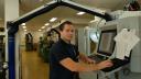 A man (Jesper) is standing in the middle of a workshop. He is looking straight into the camera. To his right is a grey milling machine. 