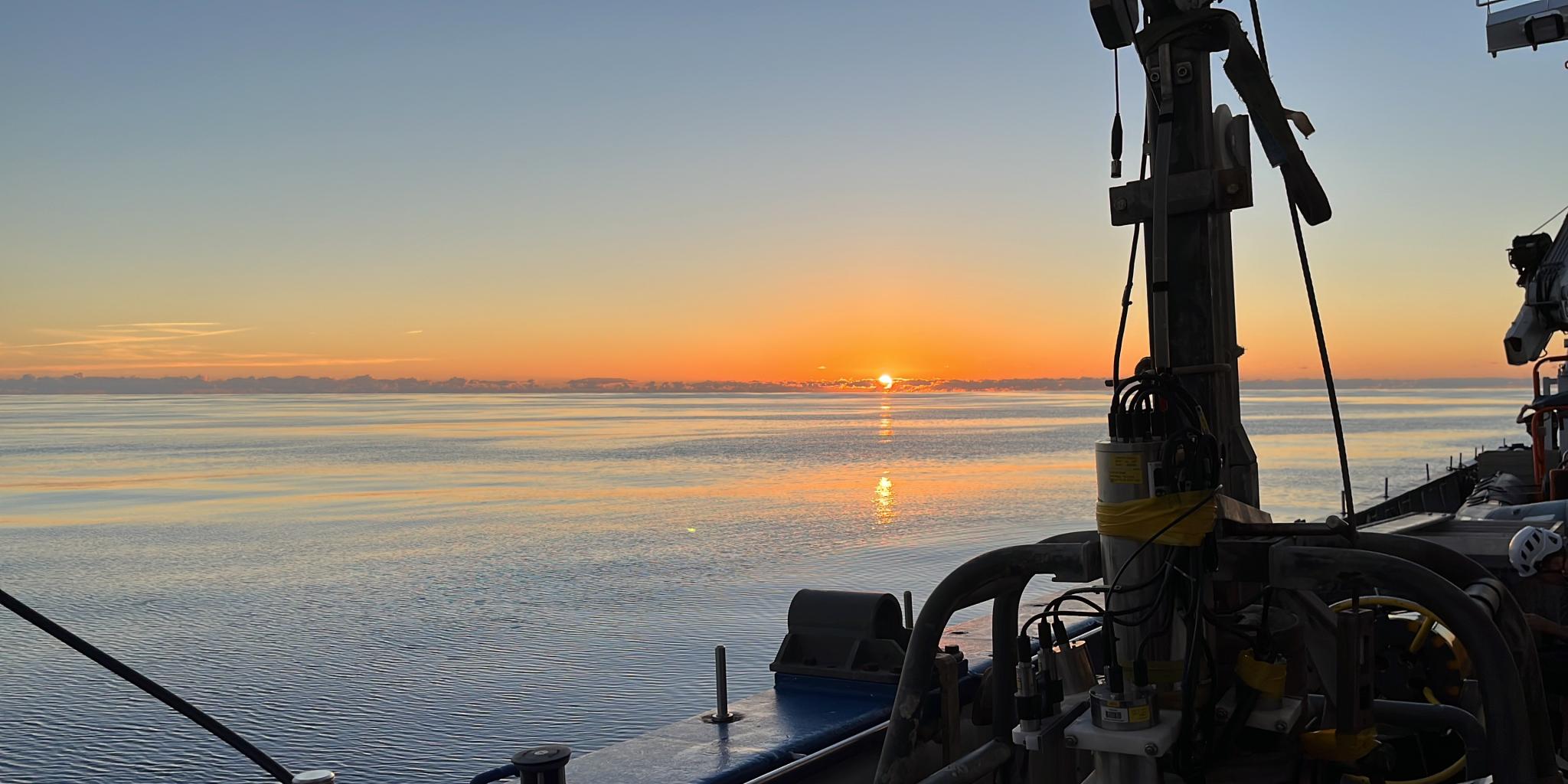 Zon die ondergaat in het water gezien vanaf het schip (RV Pelagia)