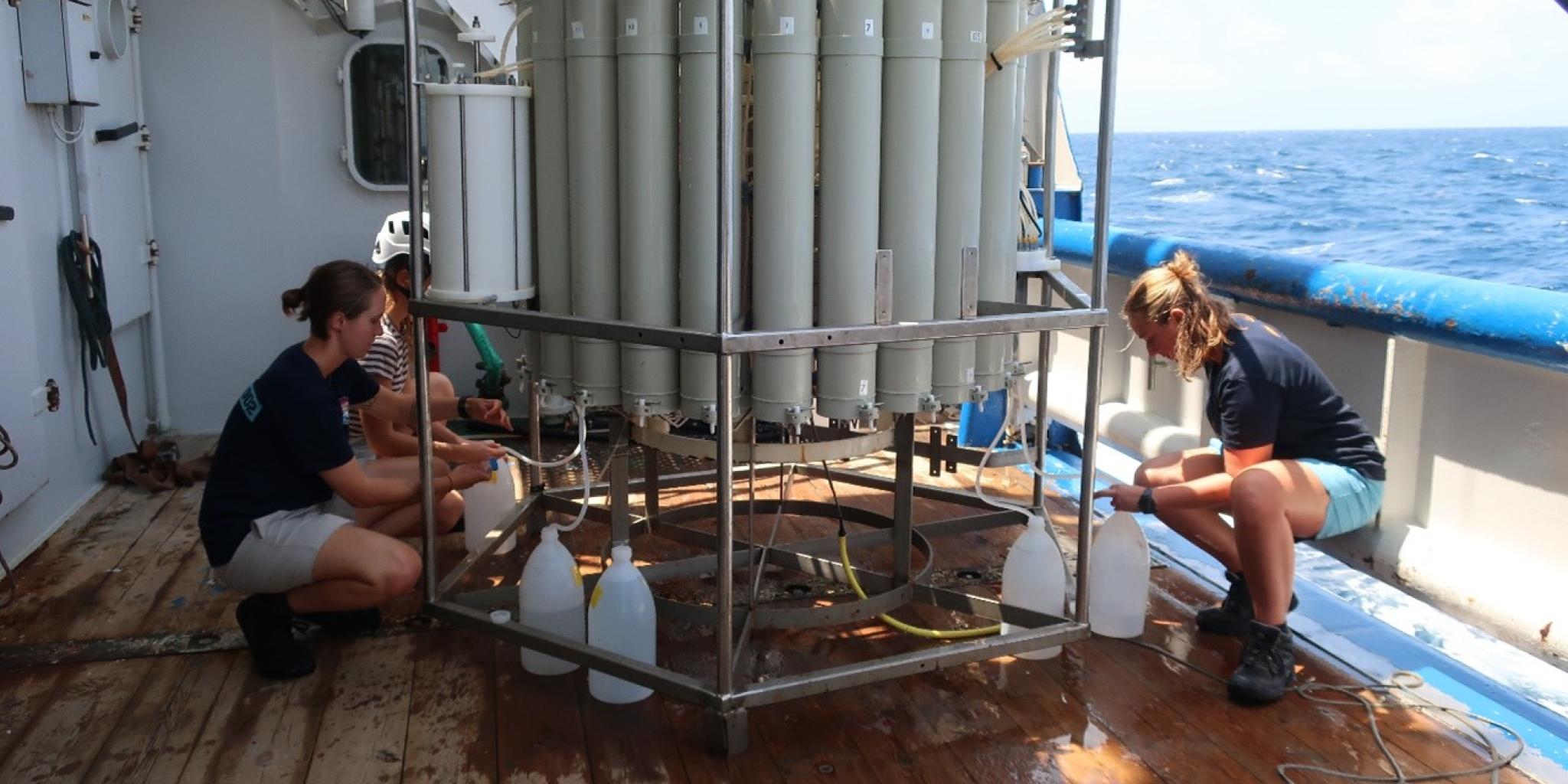 Two persons are on-board sampling of seawater using Niskin bottles that captured seawater over a range of water depths.  
