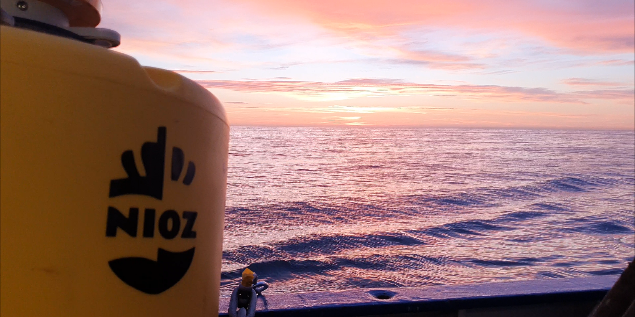 A view from aboard the ship, looking out over the ocean towards the sunset.