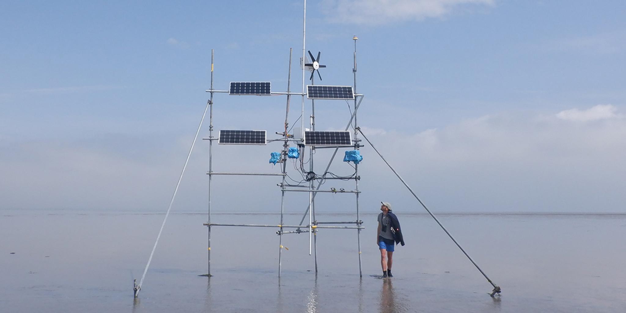 construction with solar panels above low water, a person walking by