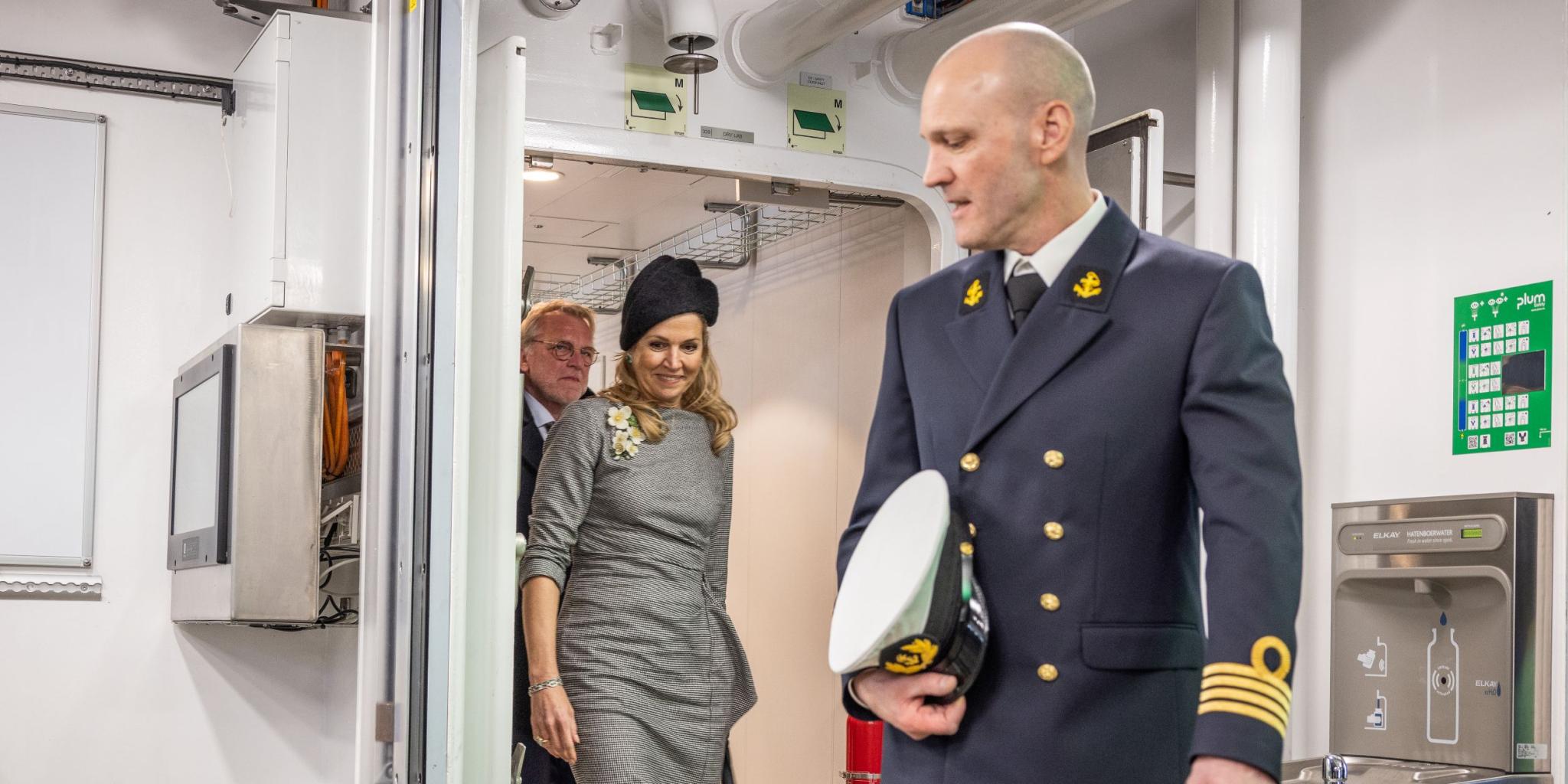 captain passing a door, followed by the queen and the NIOZ director