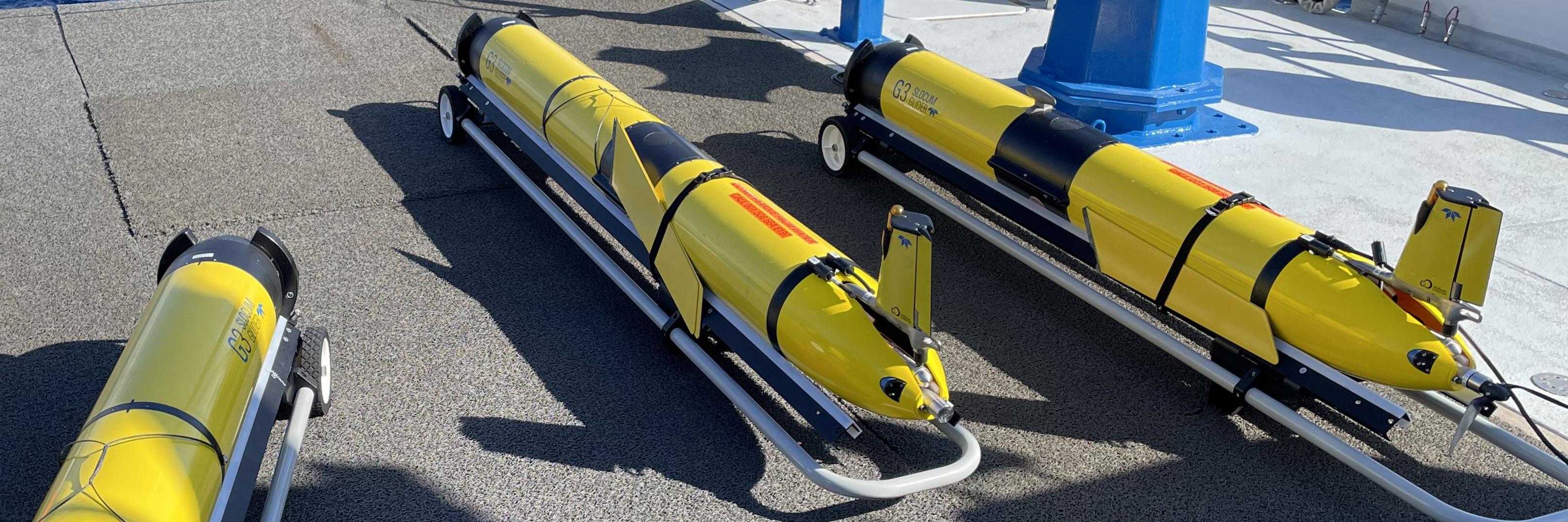 Drie gele torpedo achtige onderzoeksapparaten wachten op tewaterlating aan boord van het onderzoeksschip Pelagia.